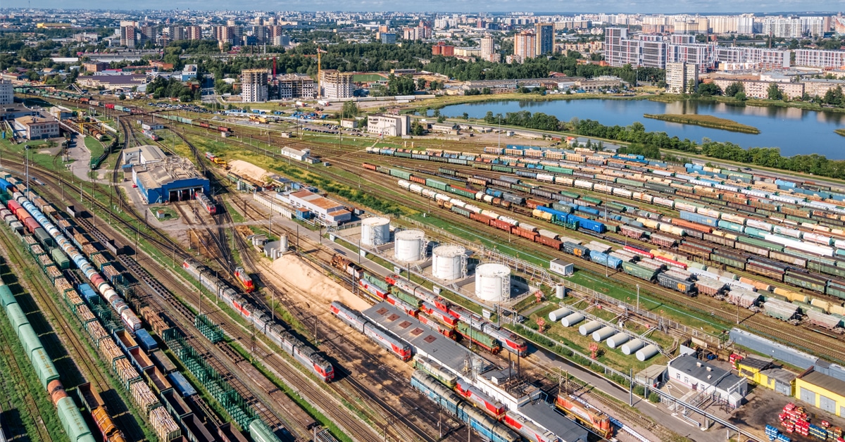 A large rail freight transloading terminal filled with lines of colorful railcars and industrial development.