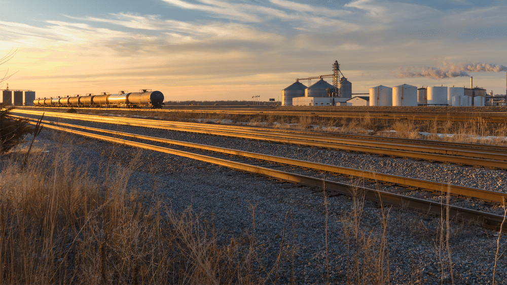 Ethanol plant located along a rail line with tanker rail cars lined up nearby.