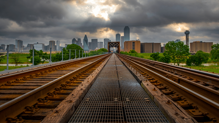 Dallas, Texas skyline under storm clouds, looking from a railroad track.