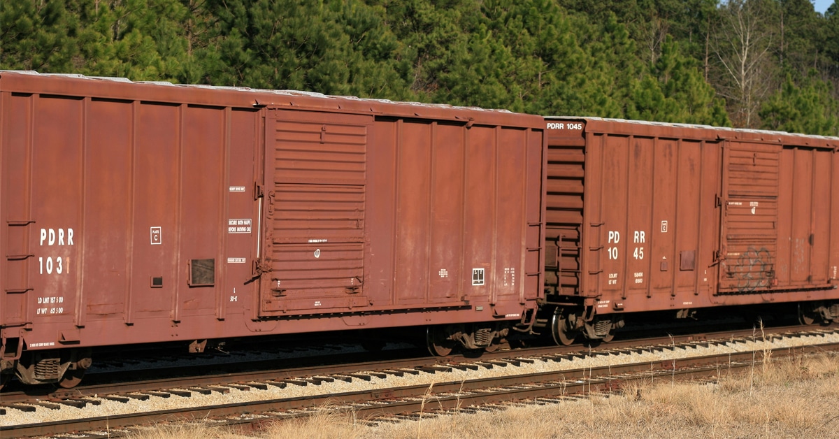 Two brown rail boxcars along a track.