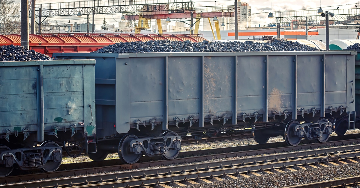 A line of grey hopper railcars with coal stored inside.
