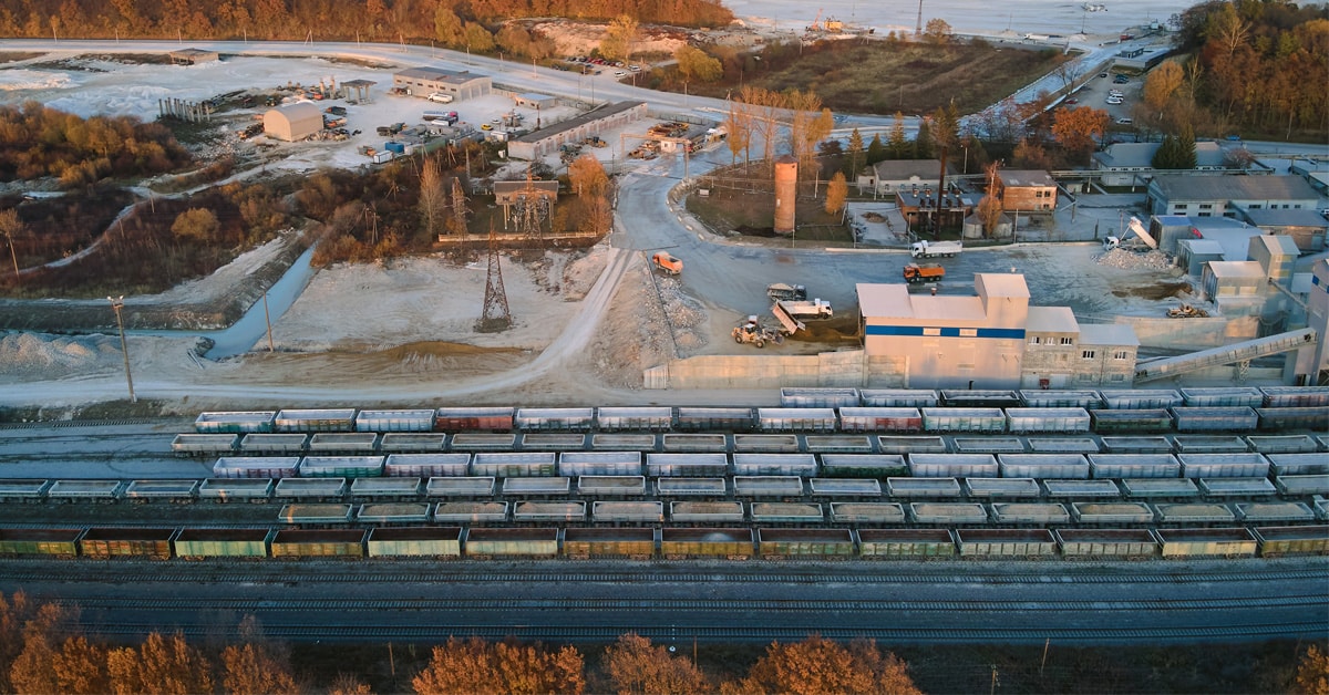 Aerial view of lines of cargo trains loaded with crushed stone materials at mining factory, an example of reciprocal switching.